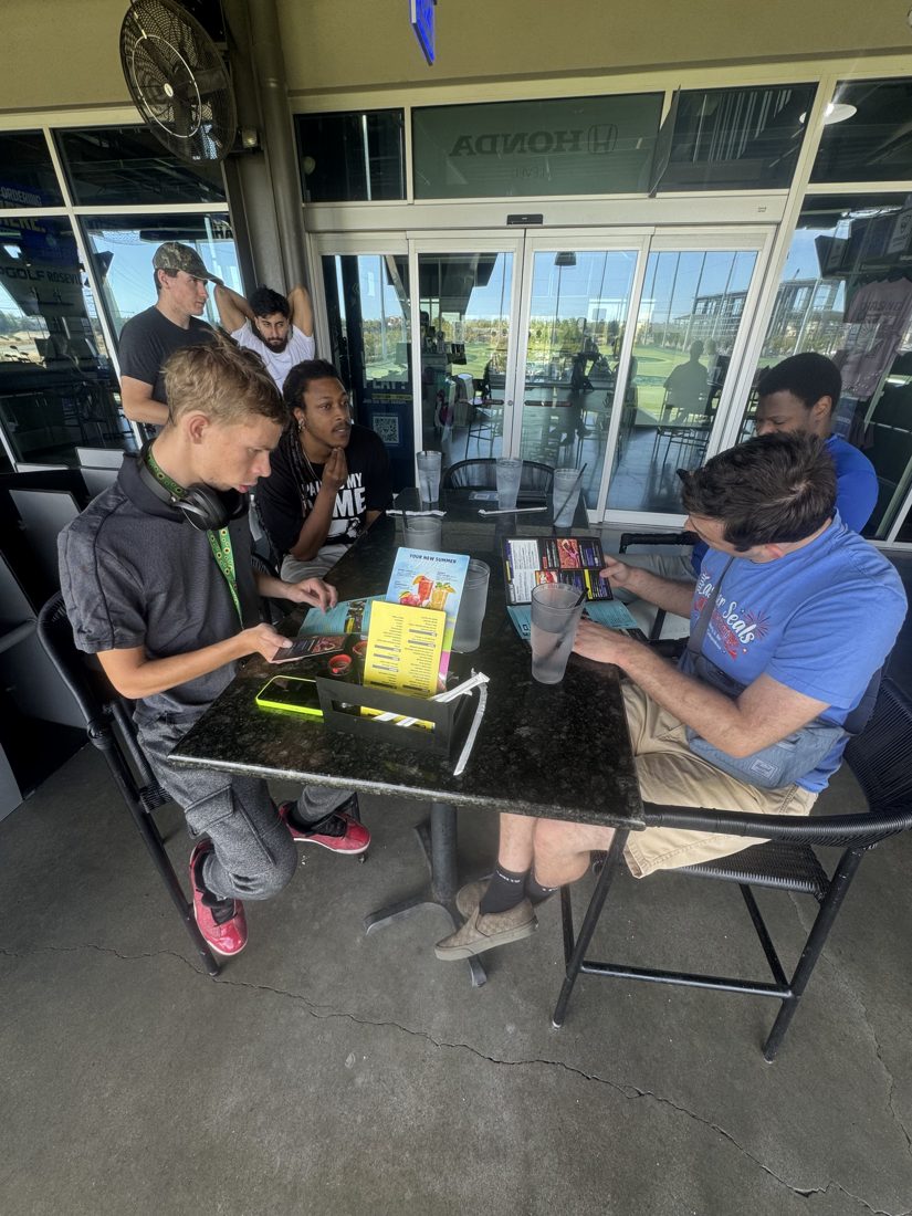 Clients and staff chatting at a Topgolf table
