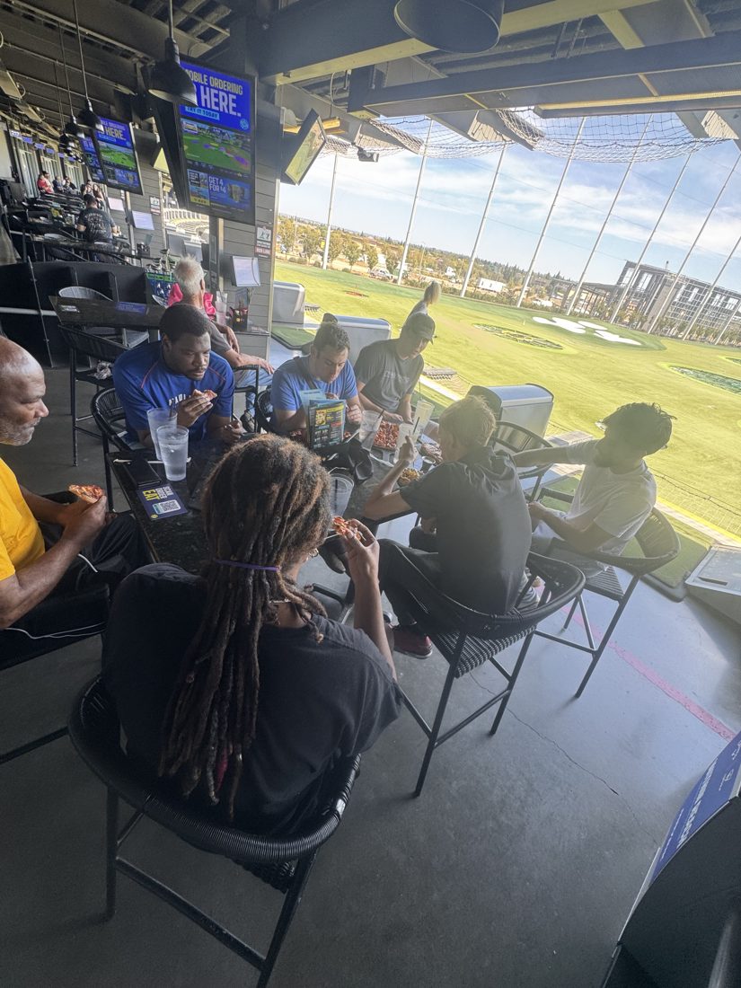 A group enjoying lunch with a view of the Topgolf range