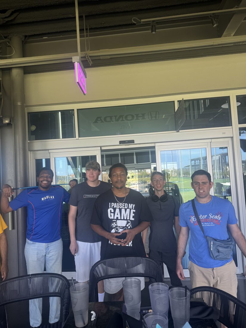Clients and staff seated at a table during a Topgolf outing